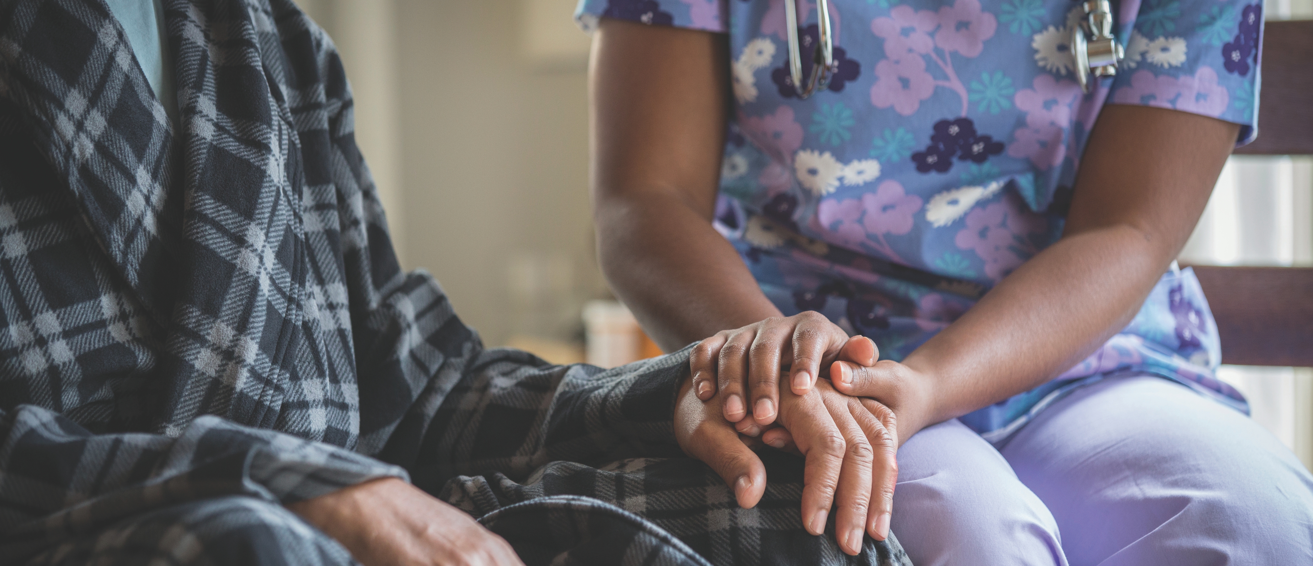 African American nurse holding patient's hand